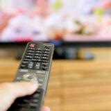 テレビとリモコンを持つ手